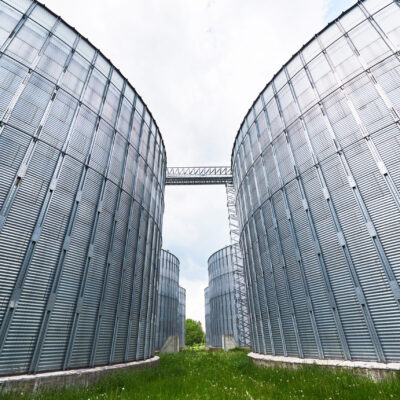 Agricultural Silos. Building Exterior. Storage and drying of grains, wheat, corn, soy, sunflower against the blue sky with white clouds.